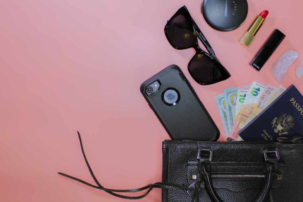 flat lay of a black purse and cell phone on a pink surface